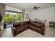 Bright living room with leather sectional sofa, tile flooring, and a balcony overlooking lush greenery at 208 Haven Beach Ct, Indian Rocks Beach, FL 33785