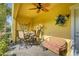 Cozy covered patio with wicker furniture, ceiling fan, and decorative wall art, perfect for outdoor relaxation and dining at 208 Haven Beach Ct, Indian Rocks Beach, FL 33785