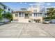 Exterior of home featuring a large concrete parking pad, front staircase, and mature trees at 30 Gulf Blvd, Indian Rocks Beach, FL 33785