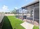 Manicured backyard featuring a screened patio with a hot tub and artificial turf at 32599 Natural Bridge Rd, Wesley Chapel, FL 33543