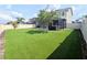 Large landscaped backyard with artificial turf, a screened-in patio, and a hot tub at 32599 Natural Bridge Rd, Wesley Chapel, FL 33543