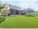 Landscaped backyard with a screened patio, hot tub, and a pristine artificial grass lawn at 32599 Natural Bridge Rd, Wesley Chapel, FL 33543