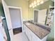 Well-lit bathroom featuring a granite countertop, white cabinets, and neutral tile flooring at 32599 Natural Bridge Rd, Wesley Chapel, FL 33543