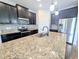 Modern kitchen featuring dark cabinets, granite countertops, stainless steel appliances, and a large island at 32599 Natural Bridge Rd, Wesley Chapel, FL 33543