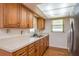 Traditional kitchen with wooden cabinets, light countertops, stainless-steel sink, and natural light at 3547 Morley Dr, New Port Richey, FL 34652