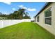 View of a green backyard with a white fence, and the side of a house with windows at 36618 Garden Wall Way, Zephyrhills, FL 33541