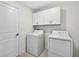 Bright laundry room features white washer and dryer, white cabinets and a door with a handle at 36618 Garden Wall Way, Zephyrhills, FL 33541