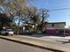 Street view of property next to commercial building, featuring mature trees, and parked car at 4009 N 15Th St, Tampa, FL 33610