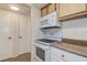 Kitchen with white appliances and wood cabinets with adjacent laundry closet at 4012 Tumble Wood Trl # 104, Tampa, FL 33613