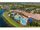 Aerial view of a beautiful community swimming pool, clubhouse, and manicured landscaping by a lake at 4911 Rock Island Ct, Wimauma, FL 33598