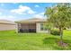Backyard view showcasing the home's screened patio and well-manicured lawn and landscaping at 4911 Rock Island Ct, Wimauma, FL 33598