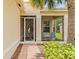 Inviting screened in front porch with brick flooring, seating, and tropical plants at 4911 Rock Island Ct, Wimauma, FL 33598