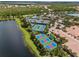 Aerial view of a community's tennis courts and lush landscaping along a lake at 4911 Rock Island Ct, Wimauma, FL 33598