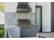 Outdoor kitchen with Lynx grill, marble backsplash and countertop, plus gray cabinets at 501 Barcelona Dr, Tierra Verde, FL 33715