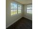 Well-lit bedroom with wood-look floors and two windows, providing natural light and a view of the outdoors at 5025 Tammy Ln, Holiday, FL 34690