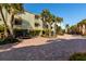 Scenic view of the condo building featuring a brick-paved parking area and lush palm trees at 505 Sandy Hook Rd # 505, Treasure Island, FL 33706