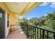 Relaxing balcony featuring a black metal railing, a wooden bench, and a view of lush greenery at 5065 Royal Palms Way # 303, New Port Richey, FL 34652