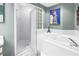 This tiled bathroom showcases a glass shower, jacuzzi tub, and a unique window of glass blocks for natural light at 5090 White Pine Ne Cir, St Petersburg, FL 33702