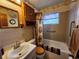Bathroom featuring a shower-tub combo, floral wallpaper, and wooden cabinets at 5221 82Nd N Ave, Pinellas Park, FL 33781