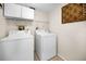Bright laundry room features white washer and dryer, storage shelves and decorative wall art at 55 Rogers St # 502, Clearwater, FL 33756