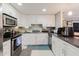 Well-lit kitchen with white cabinetry, modern appliances, and dark countertops for a functional cooking area at 5601 Golden Dr, Tampa, FL 33634