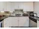 Updated kitchen with stainless steel appliances, white cabinetry, and tiled backsplash create a modern cooking space at 5601 Golden Dr, Tampa, FL 33634