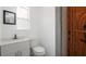 Bright bathroom featuring a white vanity, black faucet, toilet, and minimalist decor with a small mirror and window at 5725 18Th S Ave, Gulfport, FL 33707