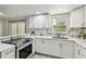 Bright kitchen features stainless steel oven and sink, marble countertops and backsplash, and white cabinets at 6200 13Th Ave, New Port Richey, FL 34653