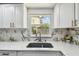 Close-up on the kitchen sink with modern fixtures, white cabinets, and natural light through the window at 6200 13Th Ave, New Port Richey, FL 34653