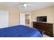 Cozy bedroom featuring a blue comforter, a dresser with a TV, and a ceiling fan at 8636 Prairie Creek Dr, New Port Richey, FL 34655