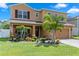 Two-story home featuring a manicured lawn, lush landscaping, and a welcoming front porch with seating at 8636 Prairie Creek Dr, New Port Richey, FL 34655