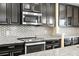 Close-up of kitchen featuring stainless steel appliances, dark cabinets, granite countertop and decorative backsplash at 8636 Prairie Creek Dr, New Port Richey, FL 34655