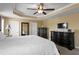 Spacious main bedroom with a tray ceiling, fan, and dark wood furniture, including dressers at 8636 Prairie Creek Dr, New Port Richey, FL 34655