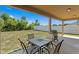 Covered patio featuring a grill, table, and chairs overlooking a spacious backyard, perfect for outdoor dining at 8636 Prairie Creek Dr, New Port Richey, FL 34655