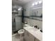 Modern bathroom with glass shower, gray cabinets, and illuminated mirror at 9161 56 Th, Pinellas Park, FL 33782