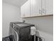 Modern laundry room featuring gray washer and dryer with white cabinets for ample storage space at 9815 Carabiner Way, Land O Lakes, FL 34637