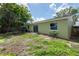View of the green home's backyard featuring a concrete patio and AC unit at 1040 Bridlewood Way, Brandon, FL 33511