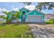 Charming home featuring a teal exterior, arched windows, well-maintained lawn, and a two-car garage at 10430 Crestfield Dr, Riverview, FL 33569