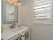 Powder room featuring white vanity with decorative mirror and window with plantation shutters at 120 Brightwater Dr, Clearwater Beach, FL 33767