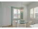 Bright breakfast nook with crystal chandelier, round glass table, and window with plantation shutters at 120 Brightwater Dr, Clearwater Beach, FL 33767