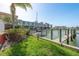 Beautiful waterfront view with a private dock, lush greenery, and a sailboat in the foreground at 120 Brightwater Dr, Clearwater Beach, FL 33767
