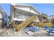 Charming beach house with a wooden staircase leading to a white balcony, a beach and outdoor seating and games at 12458 1St W St, Treasure Island, FL 33706