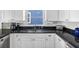 Updated kitchen with white cabinets, dark counters, stainless appliances, and tiled backsplash at 12458 1St W St, Treasure Island, FL 33706