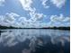 Scenic lake view reflecting the sky with lush trees lining the horizon under a partly cloudy sky at 12660 118Th St, Largo, FL 33778