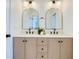 Bathroom featuring dual sinks, arched mirrors, cabinet storage, and modern fixtures at 1410 Nebraska Ave, Palm Harbor, FL 34683