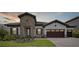 Charming one-story home showcasing stone detailing, a tiled roof, and a three-car garage at 14279 Swiss Bridge Dr, Riverview, FL 33579