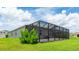 Backyard showcasing a large screened lanai, stone pavers, a lush lawn, and scenic views of the neighborhood at 14424 59Th E Cir, Bradenton, FL 34211