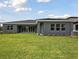 View of backyard featuring a well-maintained lawn, grey stucco and sliding glass doors at 14523 Swiss Bridge Dr, Lithia, FL 33547