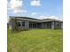 An angle of the backyard showcasing green lawn and a sleek, modern grey stucco home at 14523 Swiss Bridge Dr, Lithia, FL 33547
