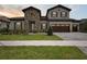 Two-story home with stone accents, wood garage doors, beautiful landscaping, and a driveway made of paving stones at 14531 Swiss Bridge Dr, Lithia, FL 33547